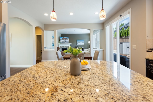 17007 NW Reuben Ln, Portland, OR 97229 - kitchen featuring a fireplace, light stone counters, recessed lighting, arched walkways, and dark wood-style flooring