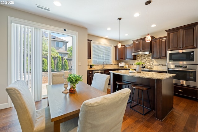 17007 NW Reuben Ln, Portland, OR 97229 - kitchen with stainless steel appliances, a kitchen island, decorative backsplash, dark brown cabinetry, and dark wood finished floors