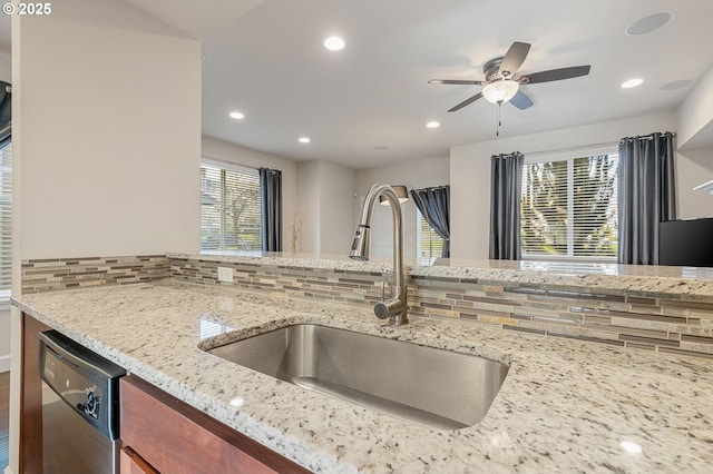 kitchen with tasteful backsplash, dishwasher, light stone counters, a sink, and recessed lighting