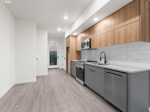 kitchen featuring sink, backsplash, light hardwood / wood-style flooring, and appliances with stainless steel finishes