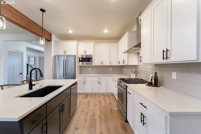 kitchen featuring sink, white cabinetry, pendant lighting, stainless steel appliances, and a kitchen island with sink