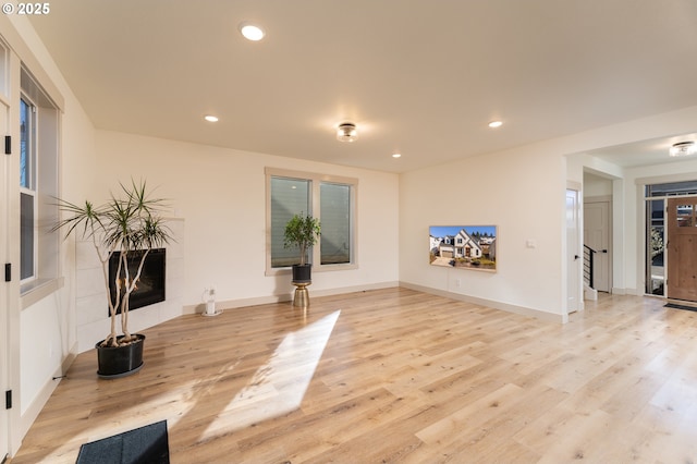 living room featuring a tiled fireplace and light hardwood / wood-style flooring