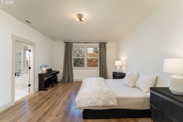 bedroom featuring connected bathroom and light hardwood / wood-style flooring