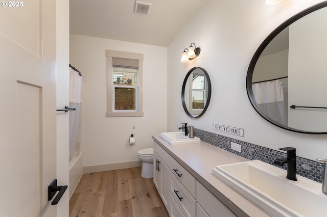 full bathroom with tasteful backsplash, hardwood / wood-style flooring, vanity, toilet, and shower / bath combo