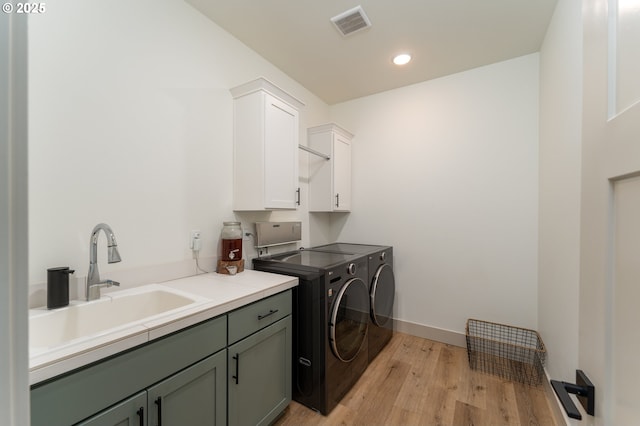 laundry area featuring light hardwood / wood-style floors, sink, cabinets, and independent washer and dryer