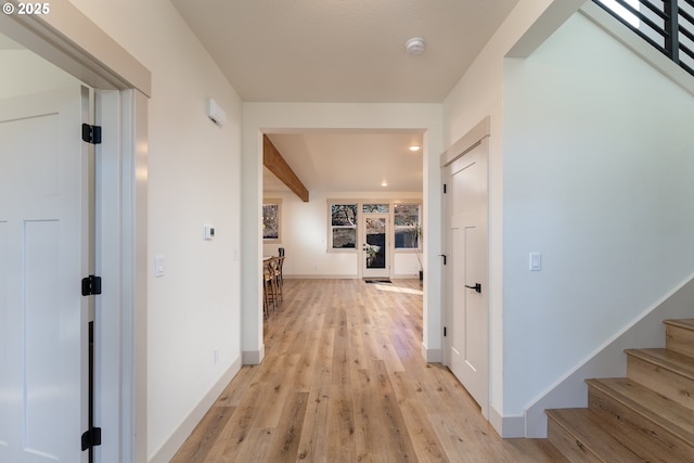 hall featuring beam ceiling and light hardwood / wood-style flooring