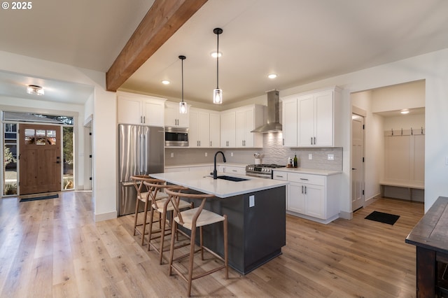 kitchen featuring appliances with stainless steel finishes, sink, white cabinets, and wall chimney exhaust hood