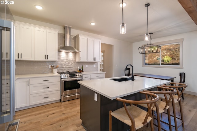 kitchen with white cabinetry, wall chimney exhaust hood, stainless steel range with gas cooktop, and sink