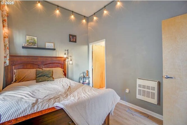 bedroom with light wood-type flooring and heating unit