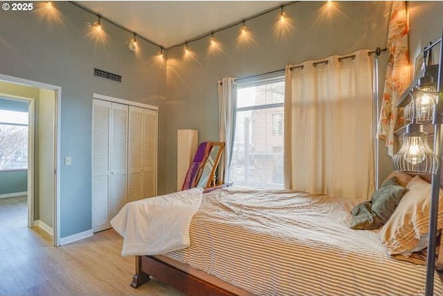 bedroom with multiple windows, a closet, and light hardwood / wood-style flooring