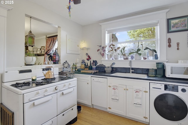 kitchen featuring white cabinets, a sink, white appliances, washer / clothes dryer, and light wood-type flooring