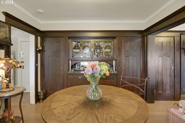 dining space with ornamental molding and light wood-style flooring