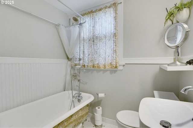 full bath featuring a sink, a freestanding bath, and toilet