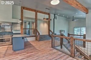 interior space featuring ceiling fan, stainless steel range, wood finished floors, and beamed ceiling