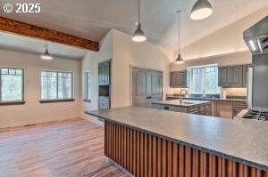 kitchen with vaulted ceiling with beams, plenty of natural light, pendant lighting, and wood finished floors