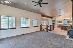 unfurnished living room featuring a ceiling fan, lofted ceiling, a healthy amount of sunlight, and carpet flooring