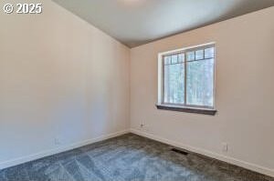 unfurnished room featuring baseboards and dark carpet