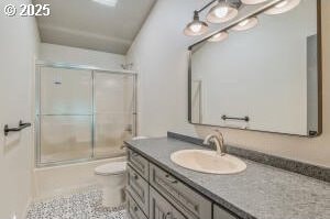 bathroom with toilet, vanity, and enclosed tub / shower combo