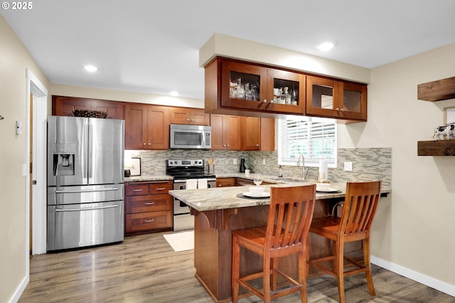 1808 S 4th St, Cottage Grove, OR 97424 - kitchen featuring stainless steel appliances, a sink, a peninsula, wood finished floors, and backsplash