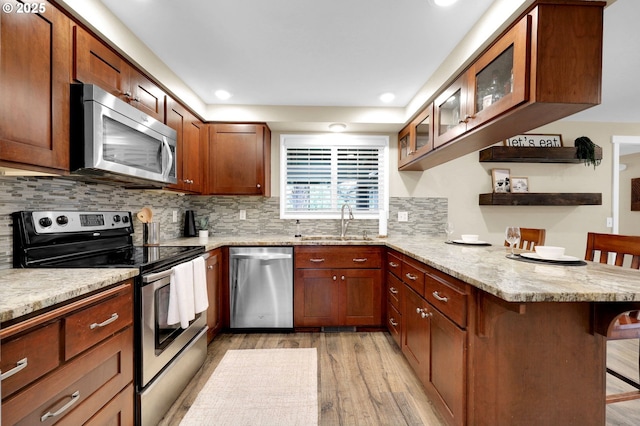1808 S 4th St, Cottage Grove, OR 97424 - kitchen featuring stainless steel appliances, a breakfast bar, a peninsula, light wood-style flooring, and a sink