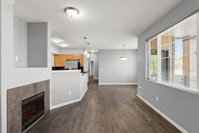 645 NW Falling Waters Ln Unit 303, Portland, OR 97229 - unfurnished living room featuring visible vents, baseboards, a tiled fireplace, and dark wood-style floors