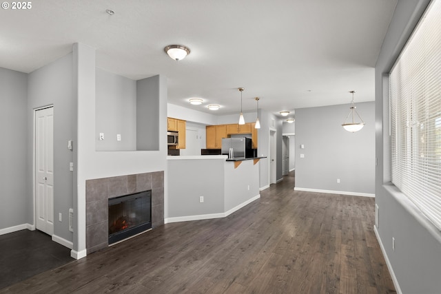 645 NW Falling Waters Ln Unit 303, Portland, OR 97229 - unfurnished living room with baseboards, dark wood-style floors, and a tiled fireplace