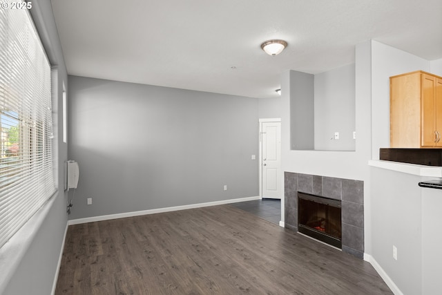 645 NW Falling Waters Ln Unit 303, Portland, OR 97229 - unfurnished living room featuring a tile fireplace, baseboards, and dark wood-style flooring