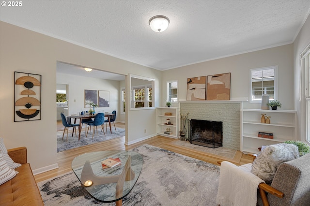 7817 N Washburne Ave, Portland, OR 97217 - living area featuring crown molding, a brick fireplace, wood finished floors, baseboards, and a textured ceiling