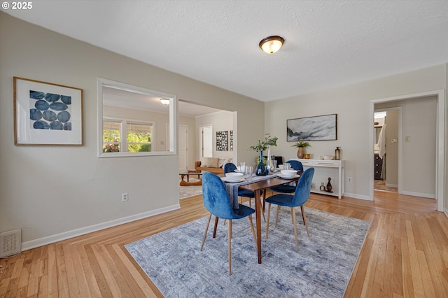 7817 N Washburne Ave, Portland, OR 97217 - dining room with a textured ceiling, baseboards, visible vents, and light wood finished floors