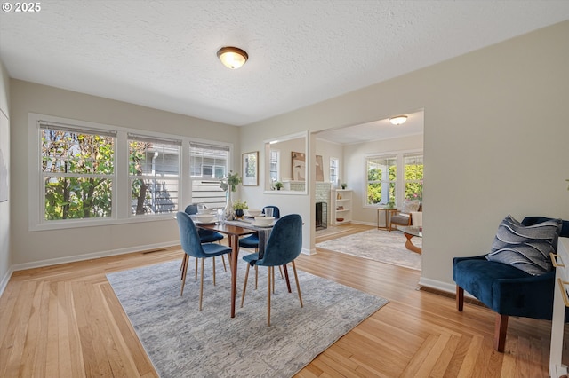 7817 N Washburne Ave, Portland, OR 97217 - dining room with baseboards, a textured ceiling, visible vents, and a fireplace