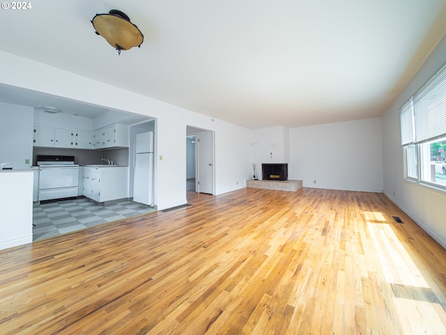 51055109 SE Tibbetts St, Portland, OR 97206 - unfurnished living room featuring light wood-style flooring, a fireplace with raised hearth, and a sink