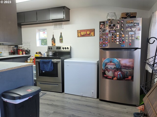 130 Aker Dr, Myrtle Creek, OR 97457 - kitchen featuring stainless steel appliances, light countertops, light wood-style flooring, decorative backsplash, and lofted ceiling