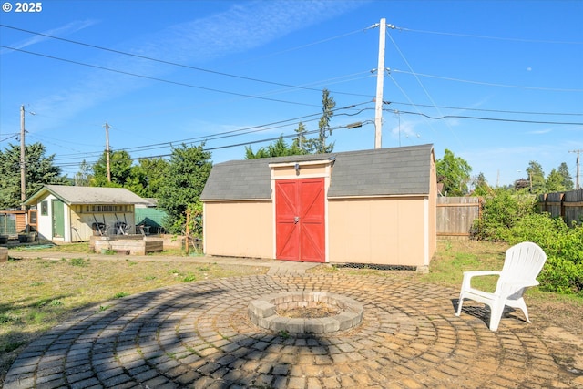 view of patio featuring fence, an outdoor structure, a fire pit, and a shed