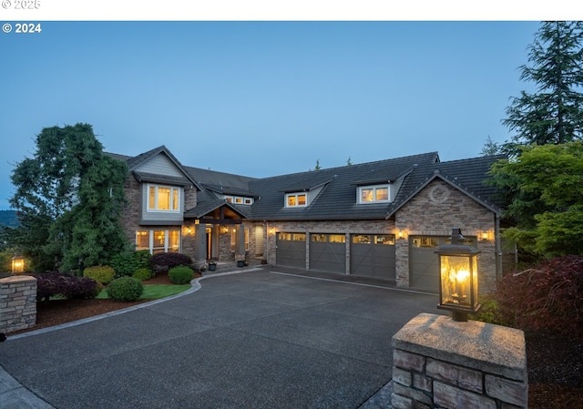 view of front facade featuring driveway, stone siding, and a garage