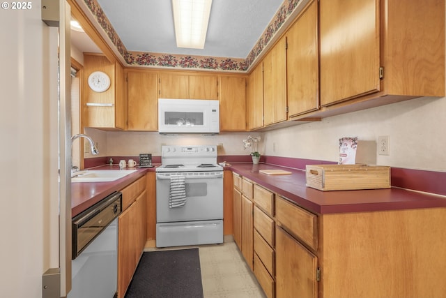 1616 N Johnson Dr, Newberg, OR 97132 - kitchen with brown cabinets, dark countertops, a sink, white appliances, and light floors