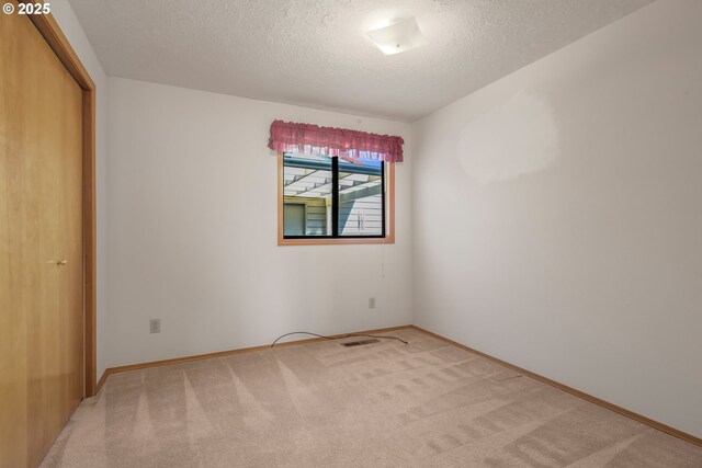 1616 N Johnson Dr, Newberg, OR 97132 - unfurnished bedroom with baseboards, visible vents, a textured ceiling, and light colored carpet
