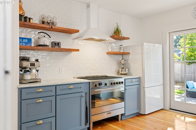 7985 SW Maple Dr, Portland, OR 97225 - kitchen with stainless steel gas stove, wall chimney range hood, open shelves, decorative backsplash, and light wood-type flooring