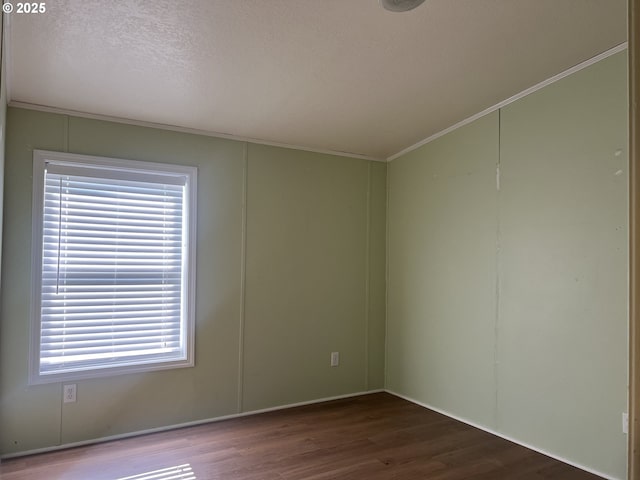 empty room featuring a textured ceiling, ornamental molding, and wood finished floors