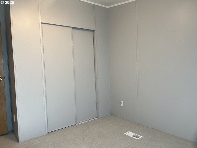 unfurnished bedroom with a closet, visible vents, and light carpet