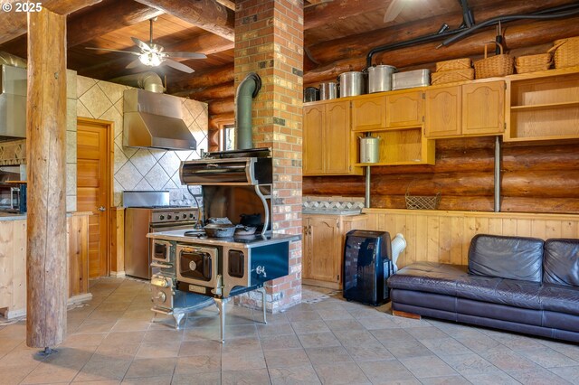 34643 Mountain View Pl NE, Albany, OR 97322 - kitchen with a wood stove, wall chimney exhaust hood, range with two ovens, rustic walls, and wooden ceiling with exposed beams