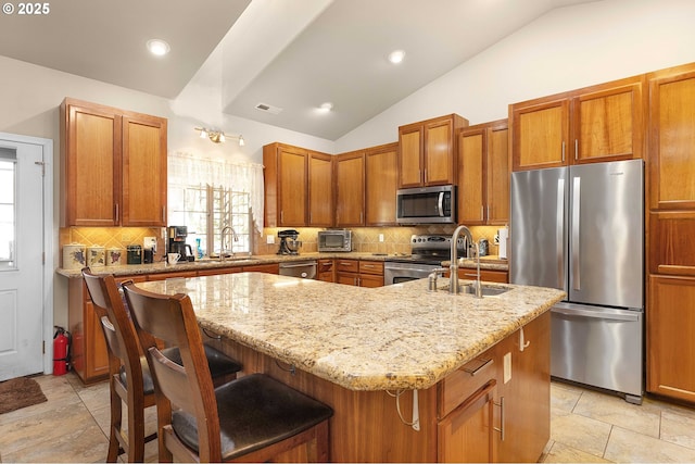 kitchen featuring visible vents, a kitchen island with sink, a sink, appliances with stainless steel finishes, and lofted ceiling