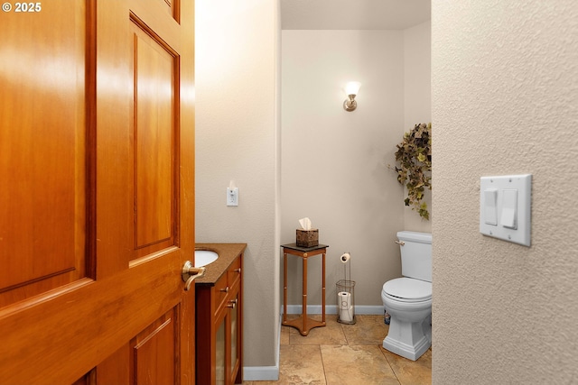 bathroom with tile patterned flooring, toilet, vanity, and baseboards