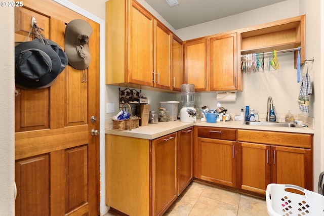 kitchen featuring brown cabinetry, light tile patterned floors, light countertops, and a sink