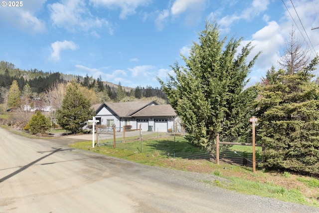 view of front facade featuring a garage, driveway, a front lawn, and fence