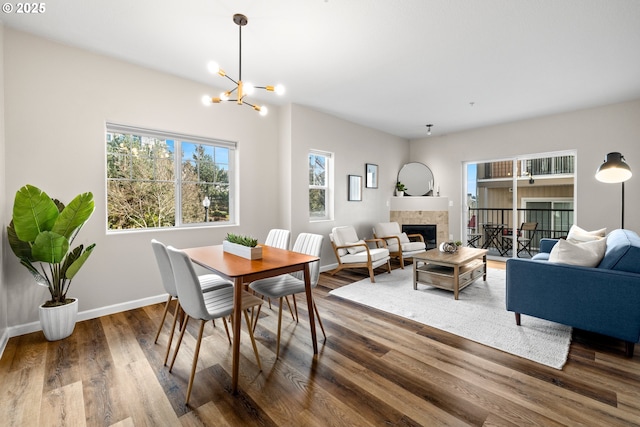 dining area with a notable chandelier, a fireplace, wood finished floors, and baseboards