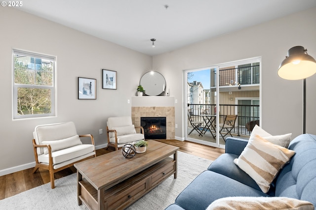 living area with light wood finished floors, a fireplace, and baseboards