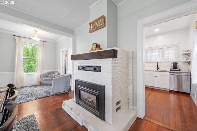 living room featuring a stone fireplace, ornamental molding, and dark wood finished floors