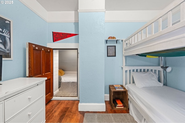 bedroom with dark wood-style floors, baseboards, and a textured wall