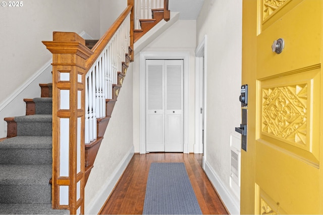 foyer with dark wood finished floors, stairs, and baseboards
