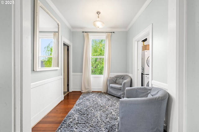 sitting room featuring stacked washer and clothes dryer, dark wood-type flooring, and ornamental molding